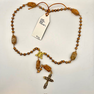 Rosary with warm amber and brown beads, elongated bead stations, a gold-toned Marian centerpiece, and an ornate cross.