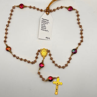 Rosary with faceted red and iridescent coin-shaped bead stations, small taupe beads, a gold-toned Marian medal, and a crucifix.