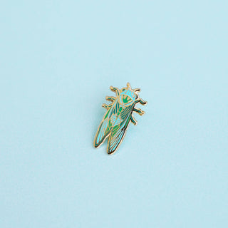 Insect-shaped pin on a light blue background